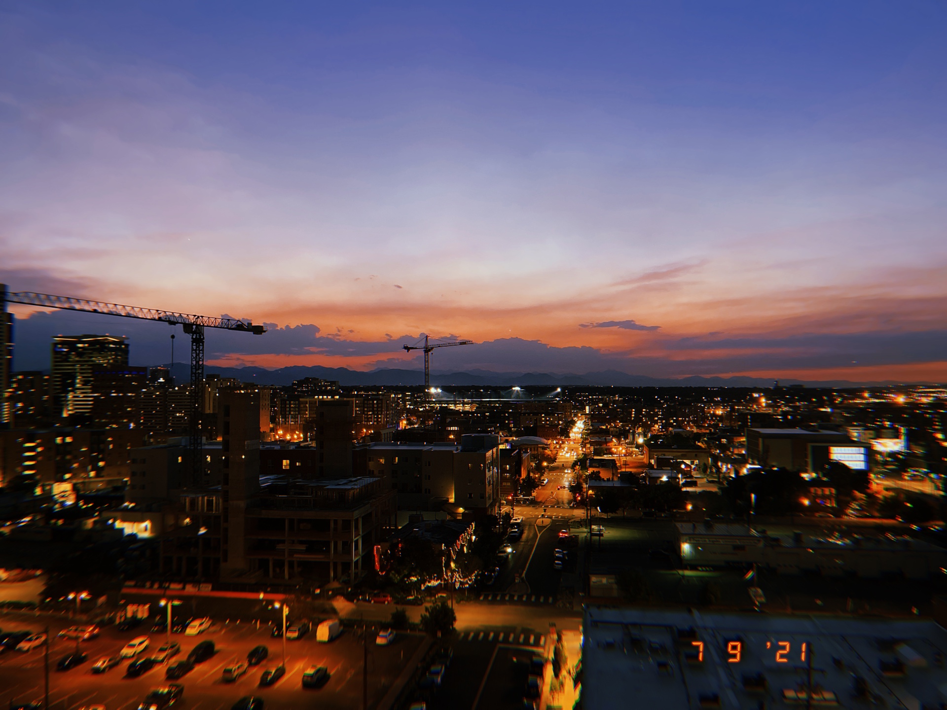Denver at dusk with city lights and mountain horizon